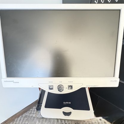 large monitor with three black tactile large buttons on bottom. Under the monitor is a built in table