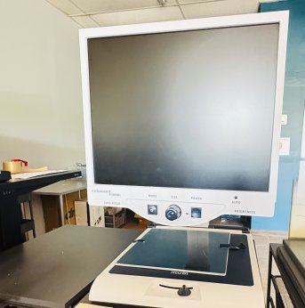 large monitor with three black tactile large buttons on bottom. Under the monitor is a built in table