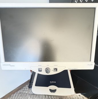 large monitor with three black tactile large buttons on bottom. Under the monitor is a built in table